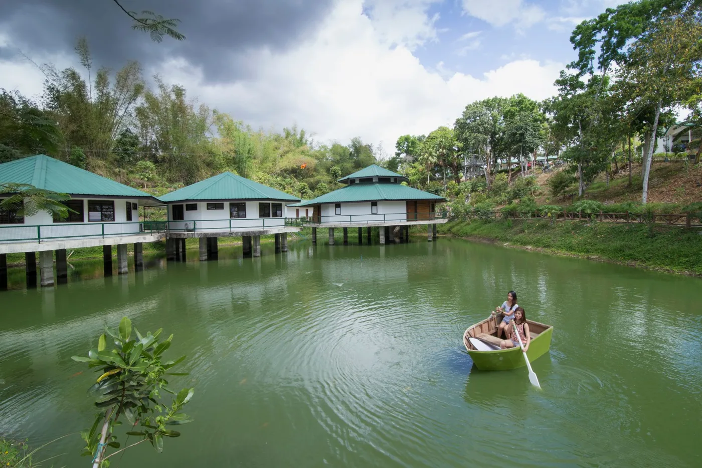 Guests rowing a boat on the lake beside the cottages on stilts