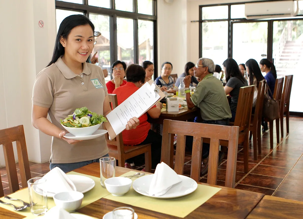 A server bringing a salad to diners in the restaurant