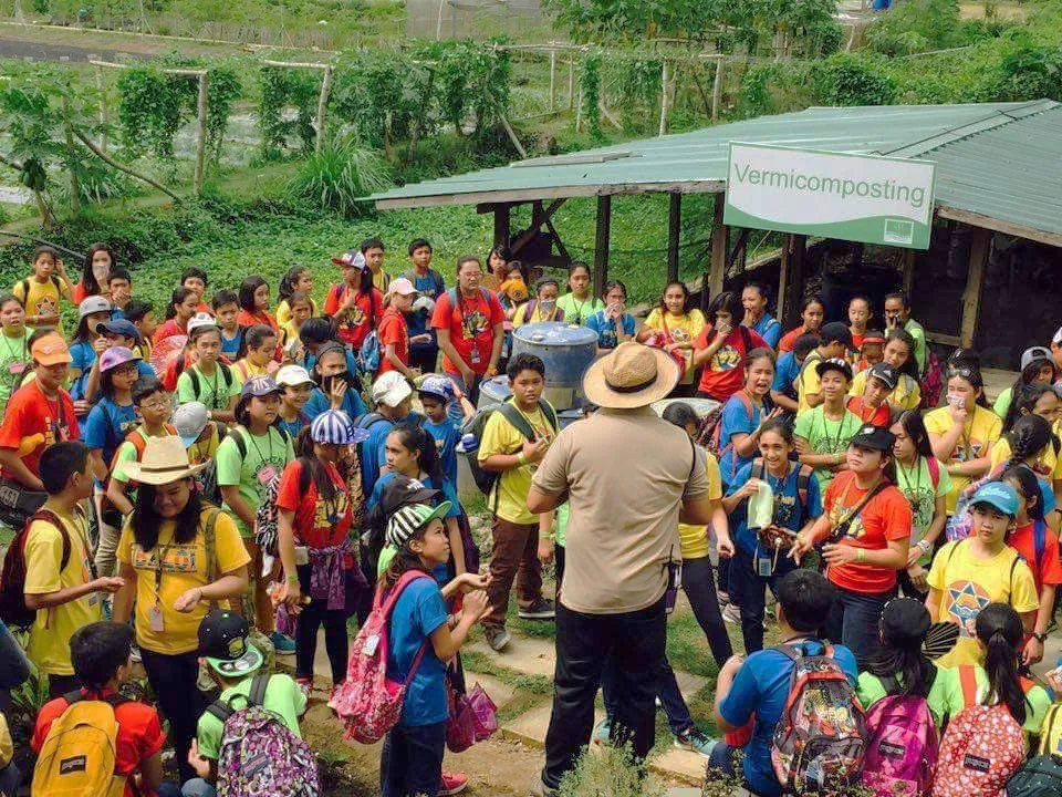 A large student group on a farm tour by the vermicomposting area